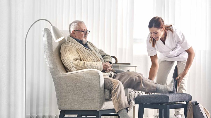 Profissional de saúde a ajudar um homem idoso
