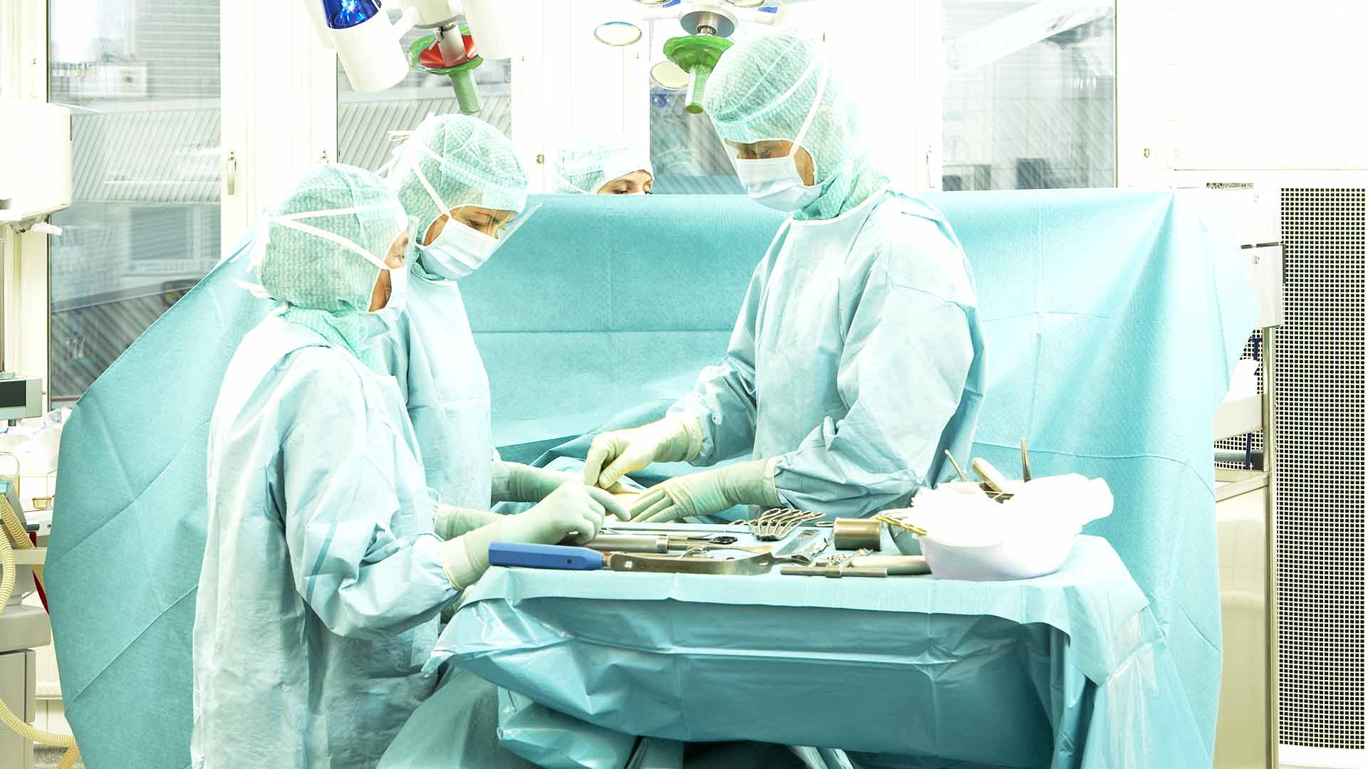 médicos no bloco operatório a preparar instrumentos cirúrgicos